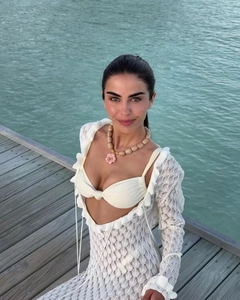 Détail de robe en dentelle blanche avec nœud et collier de perles à fleurs roses