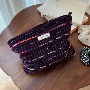 Detail of purple tweed makeup bag with colorful weave pattern and 'simple wish' label
