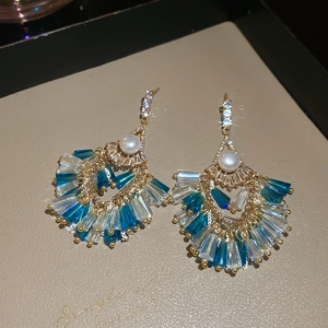 Macro shot of fan-shaped tassel earrings with blue crystals and a central white pearl