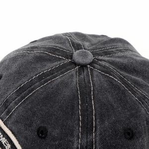 Detailed close-up of distressed dark gray baseball cap crown with white MES embroidery