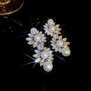 Détail de boucles d'oreilles fleurs avec cristaux scintillants et perles sur fond noir