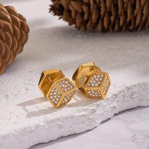 Macro shot of gold geometric cube earrings with sparkling inlaid zircon on stone base