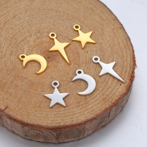 Polished stainless steel star and moon charms in gold and silver on wood slice