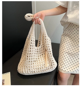 Close-up of a cream woven tote bag featuring hollow grid patterns and stylish tassel detail