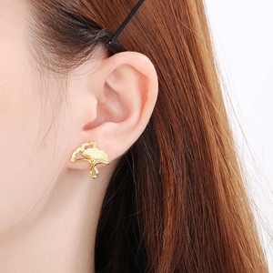 Detailed close-up of a brushed 18K gold-plated gingko leaf earring on a female ear