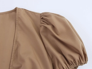 Detail view of khaki puff sleeve with elegant pleated shoulder and elastic cuffs