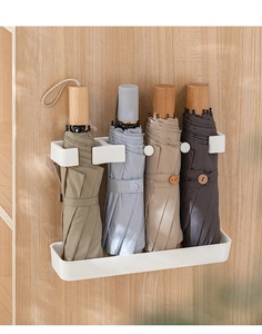 Wall-mounted white umbrella stand with a segmented design holding four folding umbrellas