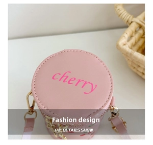 Detail of pink cylindrical bucket bag featuring cherry embroidery and gold hardware