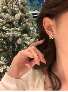 Close-up of a gold-plated rocking horse earring with cubic zirconia on a model's ear