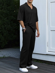 Detailed texture of black seersucker knit fabric on men's short sleeve polo and pants set