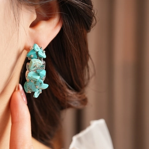 Gros plan de boucles d'oreilles en pierres turquoise irrégulières sur le mannequin