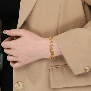 Detail of a gold butterfly charm necklace worn with a stylish beige blazer
