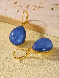Close-up of elegant gold drop earrings with deep blue translucent resin gemstones