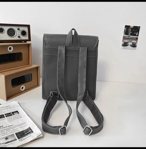 Rear view of grey leather backpack showing wide adjustable shoulder straps and metal buckles