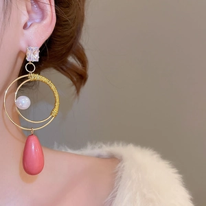Dettaglio di orecchini vintage con perle e pendenti a goccia rosa su una modella