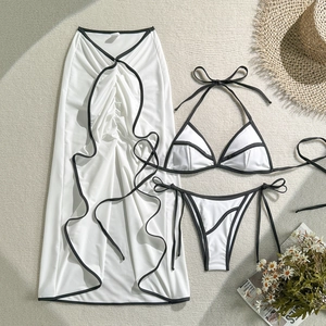 Detailed flat lay of a white three-piece bikini set with black trim and matching maxi sarong