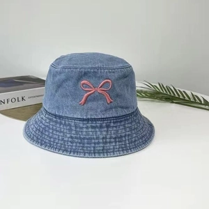 Détail du nœud brodé rose sur un chapeau bob en jean bleu à larges bords