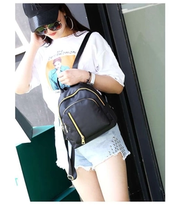 Asian model wearing a mini black nylon backpack with gold zippers for daily casual travel
