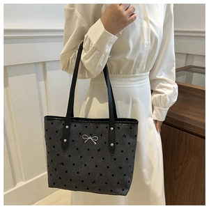 Detail der Polka-Dot-Tasche mit silbernem Metall-Schleifen-Anhänger und grauer Textur
