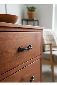 Close-up of vintage cast iron handle with embossed floral patterns on wooden drawer
