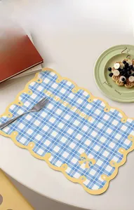 Close-up of blue gingham placemat with yellow scalloped edges and bow pattern detail