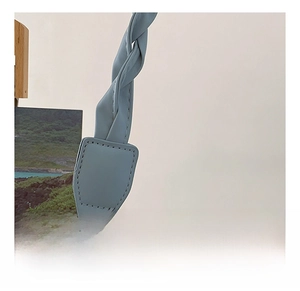 Detail of light blue crossbody bag featuring a stylish twisted shoulder strap design