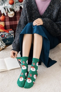 Detail of dark green Christmas socks featuring Santa Claus and gift box patterns