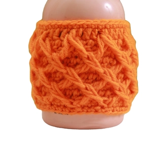 Handmade orange crochet mug sleeve with knitted diamond pattern on white background