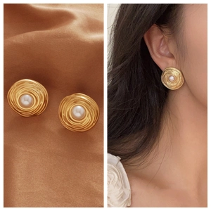 Detailed view of vintage gold spiral pearl earrings on silk and shown on a model
