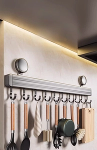 Detail of kitchen wall rack with sliding J-hooks holding utensils and a cutting board