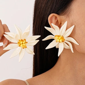 Exaggerated white resin flower stud earrings with yellow beaded centers on female model