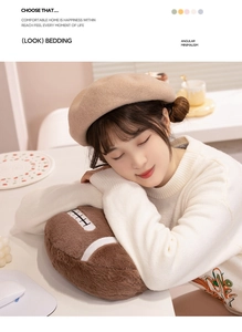 Brown plush rugby pillow with white stitching shown in a cozy home nap scene
