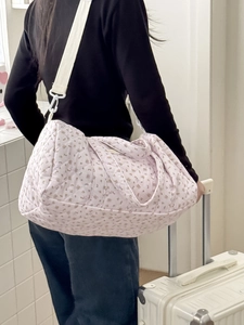 Dettaglio della borsa da viaggio trapuntata a fiori rosa con tracolla bianca morbida