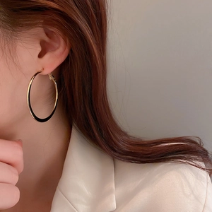 Close-up of golden large hoop earring on model showing smooth texture and high-shine finish