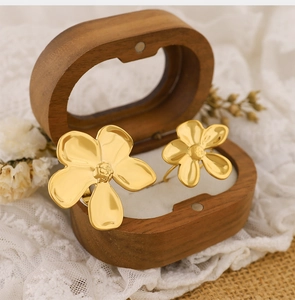 Detail of two gold flower rings on a wooden jewelry box with elegant lace background
