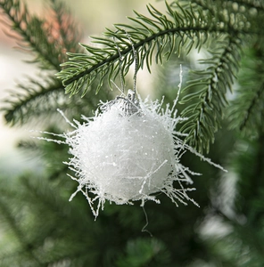 Close-up of white snowflake foam ornament with sequins hanging on a green Christmas tree