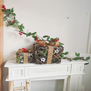 Christmas gift box decorations with red berries and pine needles on white fireplace mantle