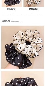 Close-up of elegant polka dot hair scrunchies in black and white fabric showing wavy edges