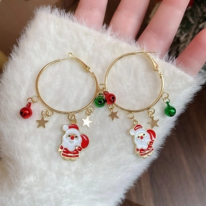 Detail of gold hoop earrings with Santa Claus charms and festive red green bells