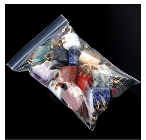 Detailed macro view of assorted natural crystal stone mini handbag pendants in a clear bag