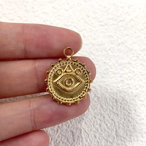 Macro shot of gold stainless steel evil eye pendant with beaded edge and top hanging loop