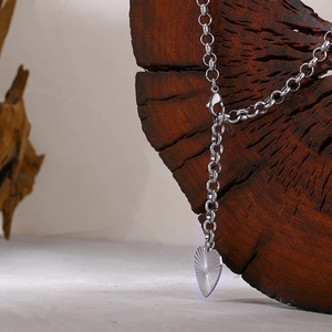 Titanium steel heart pendant necklace with sunburst radial rays on a dark wood background