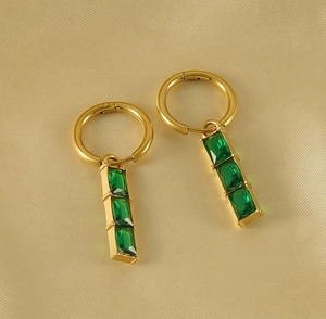 Détail de boucles d'oreilles dorées 18K avec zircons émeraude sur fond en soie douce