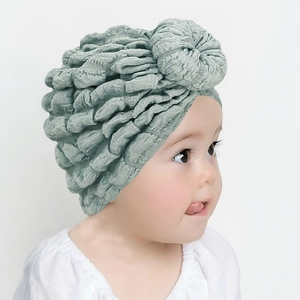 Detailed texture of light green baby donut turban hat with pleated fabric on white background