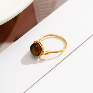 Macro shot of handmade gold wire-wrapped ring featuring a brown tiger eye gemstone