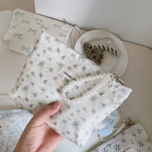 Detailed close-up of a blue floral cotton mini bag with a pearl handle and woven label