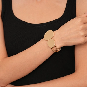 Polished gold irregular geometric cuff bracelet featuring double disc design on wrist