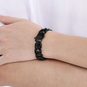 Close-up of black Cuban link bracelet on wrist showing wide metal links and polished finish