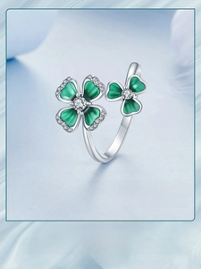 Macro shot of silver ring with two green clover leaves and sparkling zircon stones