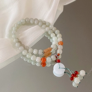 Detail eines hellgrünen zweireihigen Jade-Perlenarmbands mit Blumentaste und weißem Anhänger